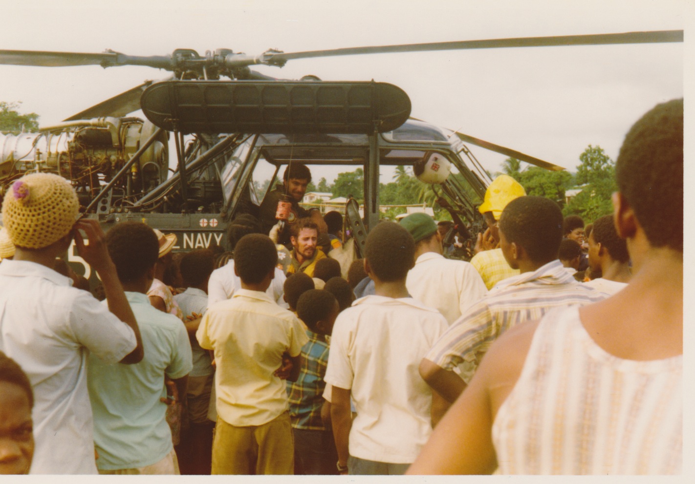 A Royal Navy Wasp helicopter surrounded by local people in Dominica